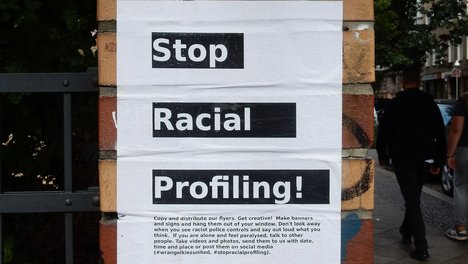 Auf einem Plakat auf einer gemauerten Säule ist zu lesen: Stop Racial Profiling