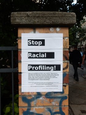 Auf einem Plakat auf einer gemauerten Säule ist zu lesen: Stop Racial Profiling